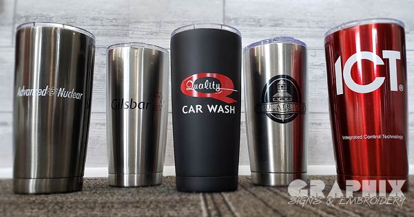Variety of stainless mugs with logos of some of our clients on them.